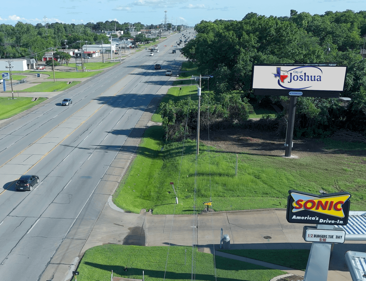 Satellite view from Google Earth showing billboard location with surrounding businesses including Sonic, Chicken Express, and Dollar General